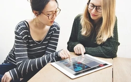 Two women reviewing data visualizations on a tablet, representing collaboration and discovering advanced features in Google Colab for data science.