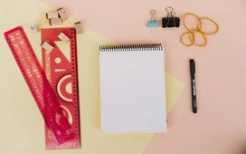 Blank notepad with rulers, binder clips, and stationery on a desk, symbolizing analyzing and comparing tools like Google Colab and Jupyter Notebook.