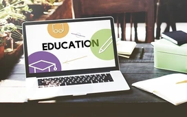 Laptop displaying education graphics on a desk with notebooks, symbolizing balancing work responsibilities with flexible free online learning.