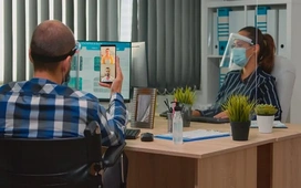 Two professionals communicating through a video call in an office, illustrating virtual teamwork and how to find remote project management job opportunities.