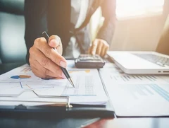 A professional reviewing financial statements with a pen and calculator, illustrating skills gained through free online accounting courses with certificates.