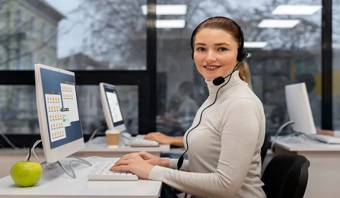 Customer service agent with headset at computer using AI tools – AI and customer service trends for 2024
