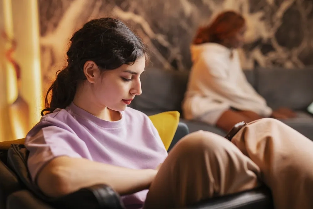 Young woman sitting alone and looking down thoughtfully, representing emotional struggles and symptoms linked to borderline emotional disorder.