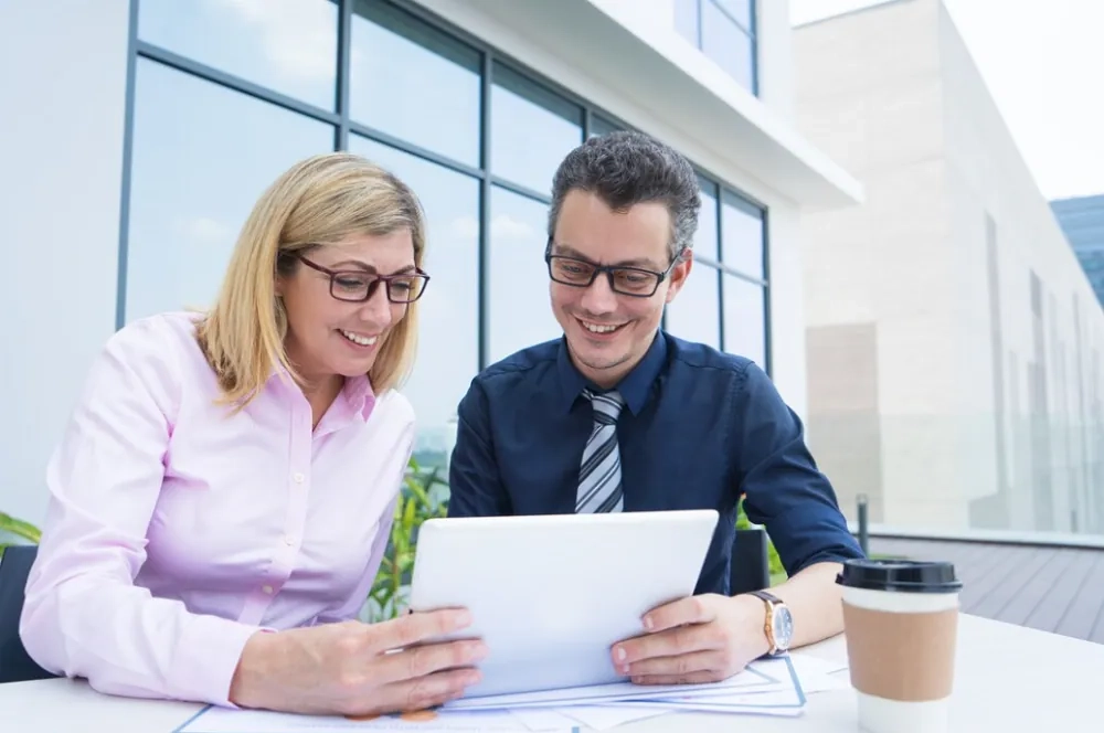Two professionals reviewing information on a tablet, representing the role, responsibilities, and meaning of becoming a Certified Public Accountant.