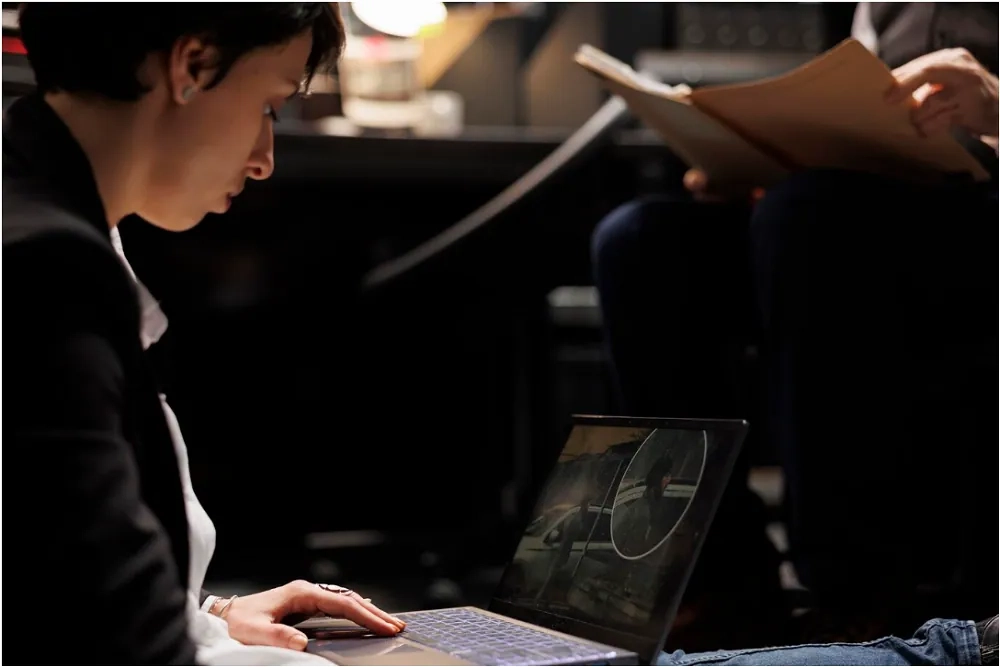 Investigator reviewing surveillance footage on a laptop while another examines files, representing forensic accounting in financial crime investigations.