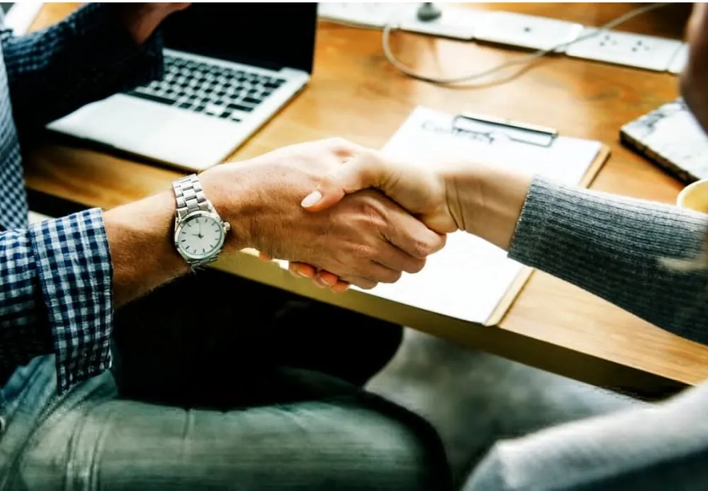 Two people shaking hands in a professional setting, symbolizing strong customer relationships and effective customer interaction management.