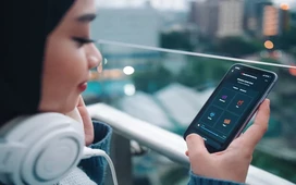 Young woman with headphones using her smartphone outdoors, symbolizing flexible digital learning and staying engaged while mastering an academic curriculum.