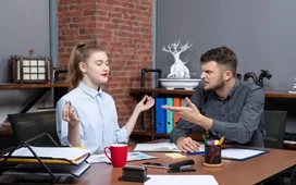 Two colleagues in a workplace discussion, illustrating active listening and clear communication skills for professional success.