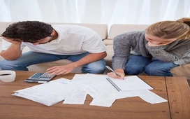 Two individuals reviewing documents and calculations at a table, symbolising data organisation and analysis used in EMIS systems.