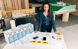 Female professional reviewing building plans and models, representing planning, coordination, and responsibilities of a modern facilities manager.