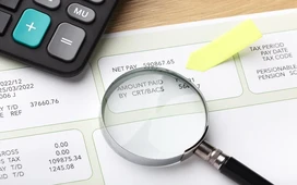 Magnifying glass and calculator examining financial documents, symbolizing fraud detection and investigation in forensic accounting courses.