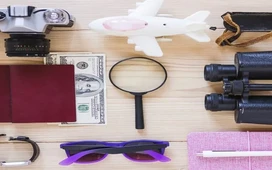 Forensic auditing tools including magnifying glass, documents, camera, and money arranged on a desk to represent fraud investigation methods.