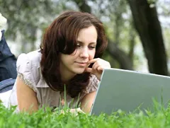 Woman studying online on a laptop while relaxing outdoors, representing convenient and flexible access to free distance learning programs.