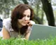 Woman studying online on a laptop while relaxing outdoors, representing convenient and flexible access to free distance learning programs.