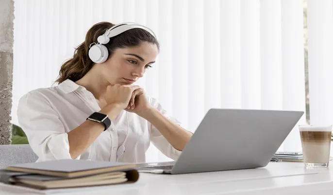 A young woman studying online with headphones and a laptop, representing how free online courses can help develop skills for job opportunities.