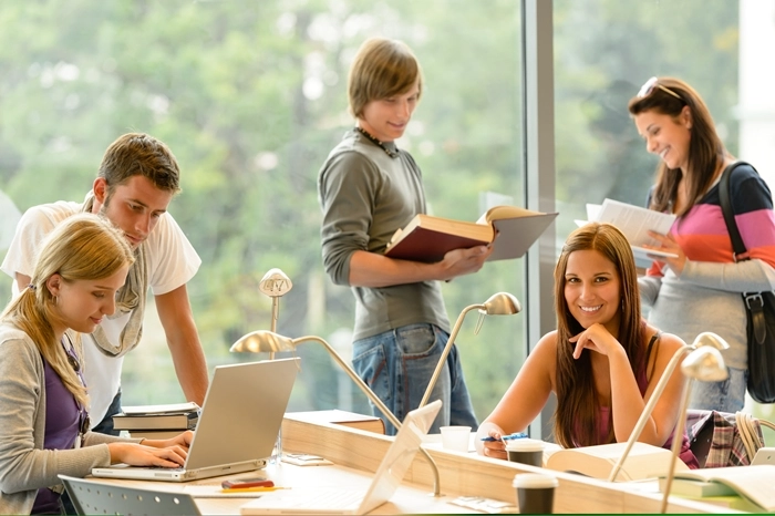 Group of students studying with laptops and books in a bright study area, representing flexible learning through free online courses.