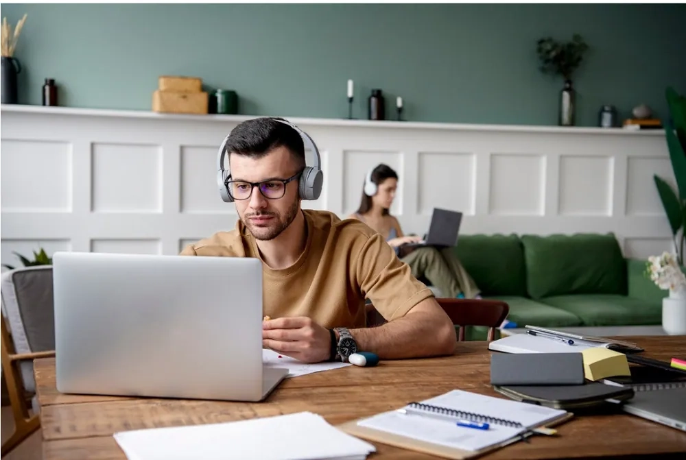 Man studying on laptop with headphones at home – free online courses with certificates to boost your career.
