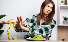 Woman refusing junk food and holding measuring tape beside salad – simple tips to lose weight fast safely