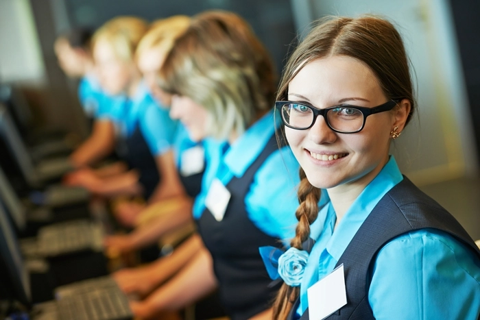 Hospitality staff in uniform assisting guests at service desks, illustrating customer care and hospitality management roles.