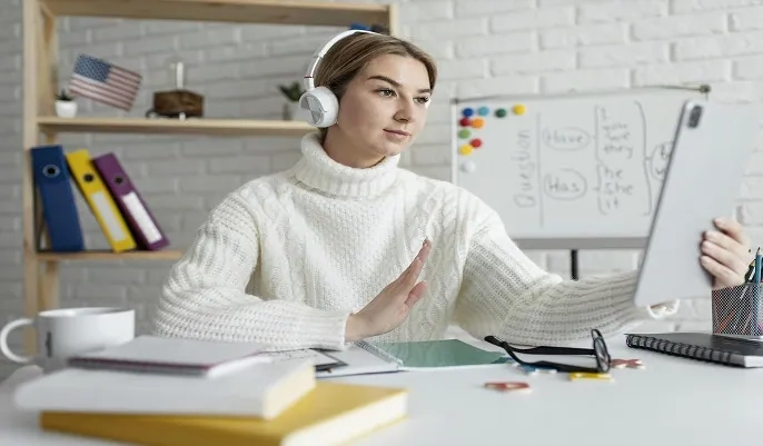 Woman studying online with headphones and a tablet in a home workspace, illustrating how OHSC’s free online courses can easily fit into a busy lifestyle.