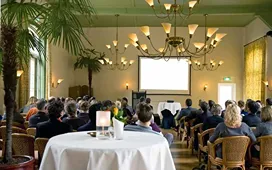 Audience attending an indoor event with a presentation screen, representing event coordination and skills needed for event management careers.