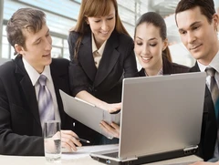 Business professionals reviewing documents and a laptop together, representing attractive job opportunities after business studies.