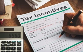 Person completing a tax incentives form with a calculator nearby, representing income tax management and setting up a personal tax account.