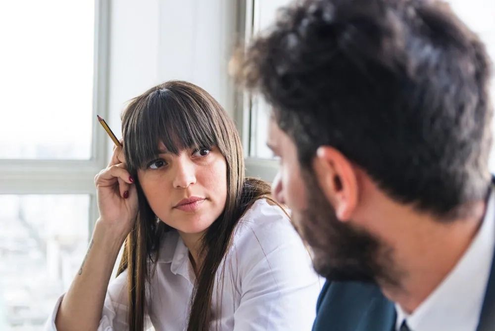 Woman listening attentively to colleague during meeting, showing the difference between hearing and active listening skills.