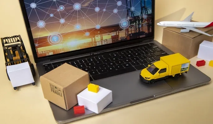 Laptop displaying global logistics network with miniature truck, plane, and packages, illustrating modern supply chain management roles.