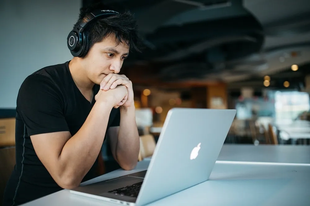 A student using a laptop and headphones while studying online, representing emerging learning trends and new technologies in 2024.