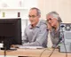 Older couple learning on a desktop computer at home, showing online study and lifelong education at any age.