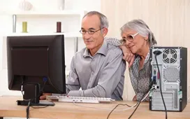 Older couple learning on a desktop computer at home, showing online study and lifelong education at any age.