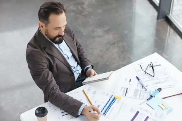 Project manager reviewing plans and charts at a desk – PMP certification guide to successful project management.
