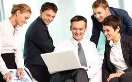Business team smiling and discussing ideas around a laptop, representing collaboration, innovation, and motivation to start a business.