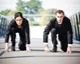 Two business professionals in a race-start pose, symbolising workplace competition and the drive to earn a promotion.