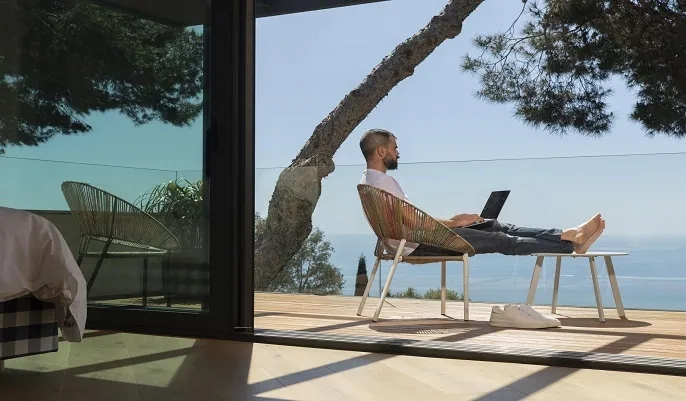 A man working remotely on a laptop while relaxing outdoors, symbolizing the growing trend of remote work and the skills needed for 2025’s top jobs.