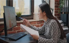 Woman working remotely on a computer while reviewing notes, representing online data entry careers and the flexibility of remote administrative work.