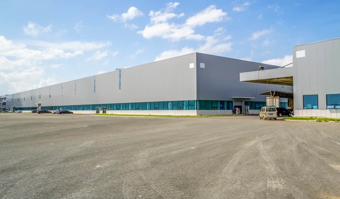 Large modern warehouse building with wide exterior space, representing career opportunities and growth in warehouse management.