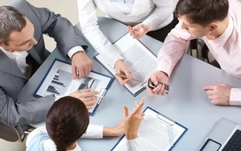 Business team reviewing reports and charts in a meeting, illustrating collaboration and decision-making in strategic planning.