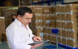 Warehouse manager checking inventory on a tablet, showing the practical value of studying supply chain certification.
