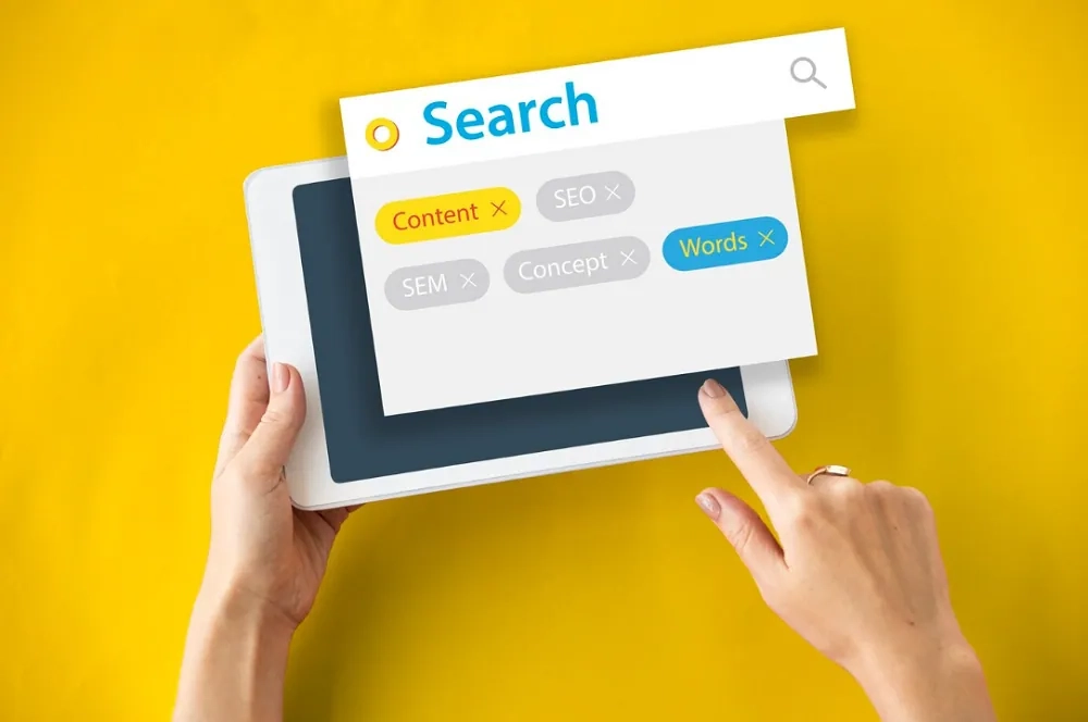 Hands using tablet with search bar and SEO tags, representing website search optimization strategies by OHSC.