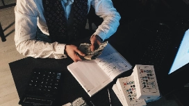 Accountant counting cash beside ledger and calculator – explore accounting and finance short courses online with OHSC