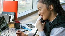 Professional communicating by phone at a desk, demonstrating communication and communication skills in administration