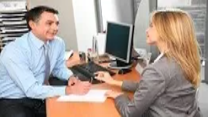 Two office professionals discussing documents at a desk, representing advanced administrative, secretarial, and PA skills at QLS Level 3.