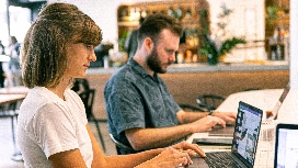 Freelancers collaborating on laptops in a shared workspace, managing projects and client relationships online