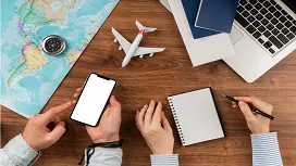 A travel planner uses a smartphone, map, notebook and travel documents, representing advanced planning and industry skills taught in Level 5 travel and tourism courses.