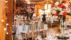 Luxurious wedding reception with elegant floral centerpieces, golden chairs, and decorative lighting, illustrating advanced wedding planning skills.