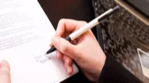 A person writing notes on a document, symbolising the development of professional communication and advanced writing skills taught in Level 3 courses.