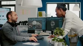 Two colleagues reviewing 3D digital models on computer screens, illustrating how AI supports project planning, design, and workflow optimization.