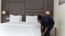 Hotel staff member preparing a neatly made bed, representing service quality and enhanced guest experience supported by AI-driven hotel marketing strategies.